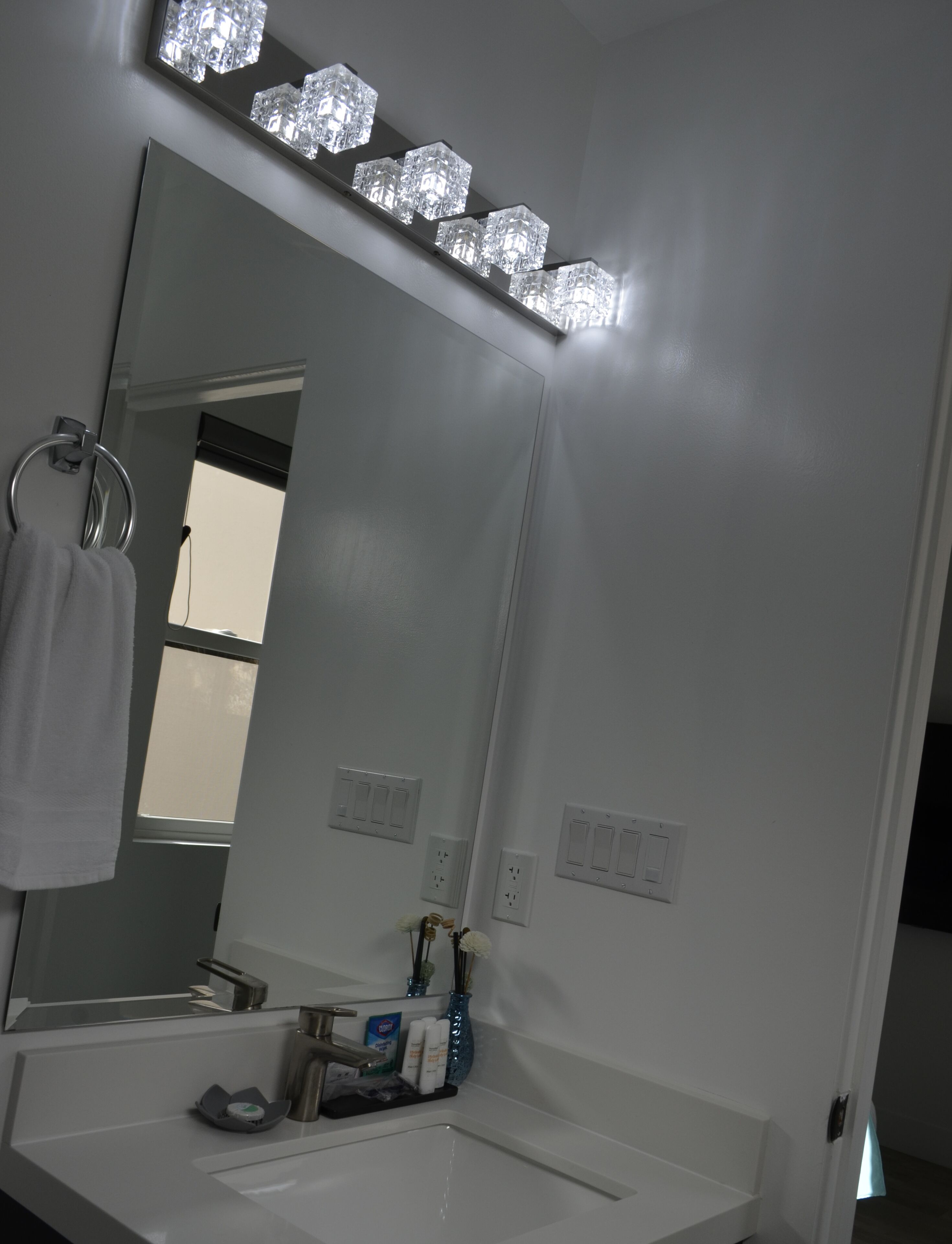 A bathroom with a large mirror, a sink, and a vanity.