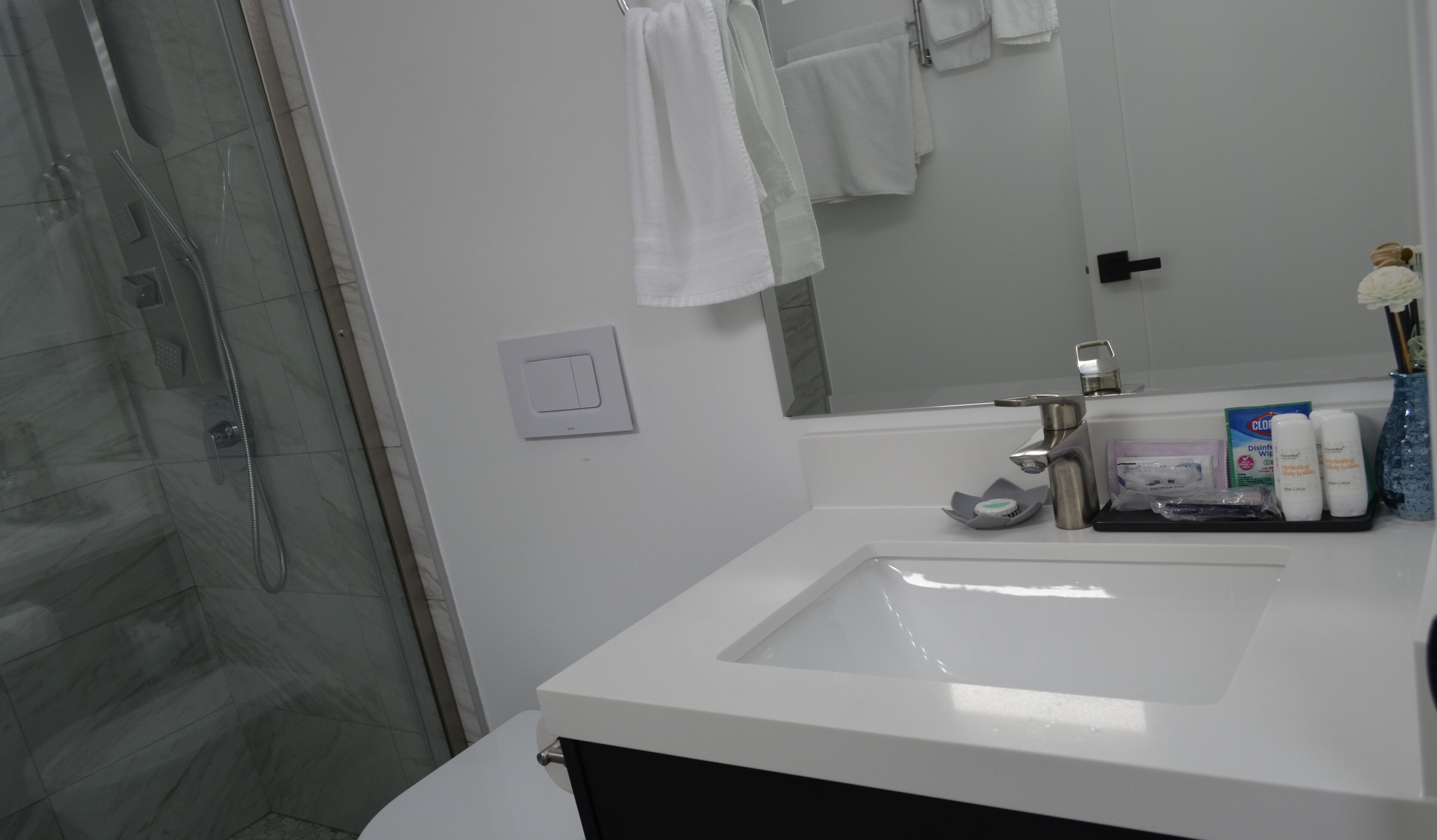 A modern bathroom with a white sink, a glass shower enclosure, and a mirror.