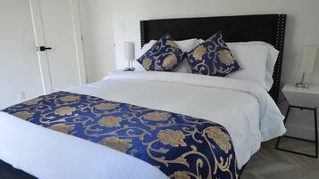 A neatly made bed with a blue and gold patterned bedspread, white pillows, and a dark headboard.