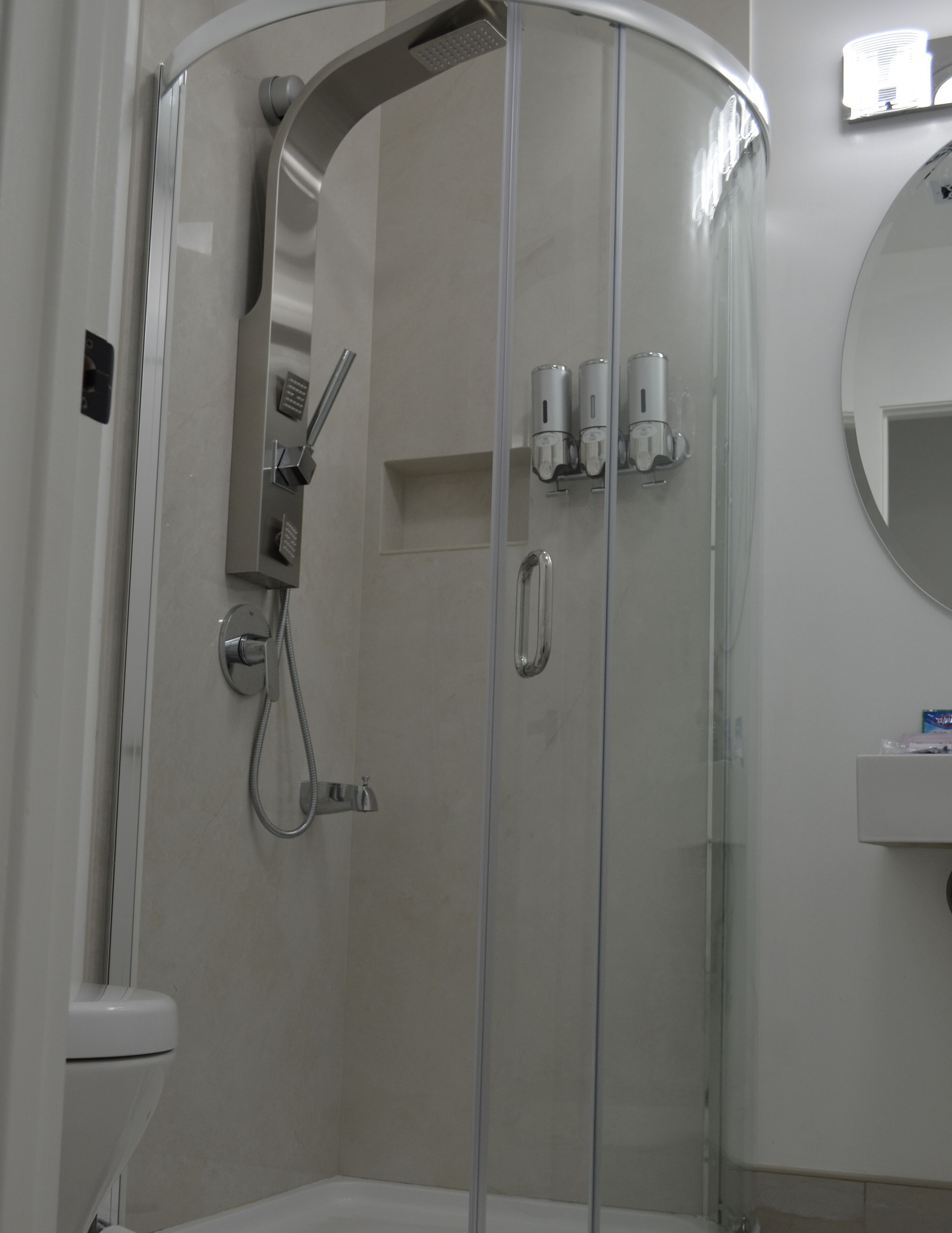Ein modernes Badezimmer mit einer Duschkabine, einer Toilette und einem Waschbecken mit Spiegel darüber.