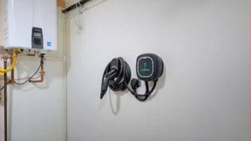 A wall-mounted electrical outlet with a power cord and a device plugged in.