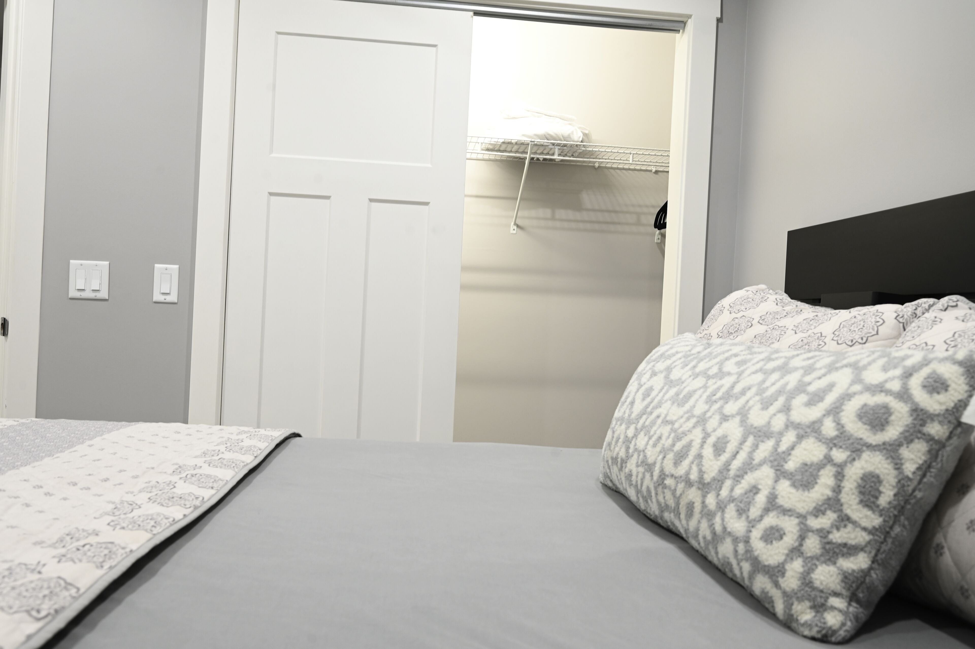 A bedroom with a bed, a wardrobe, and a closet with a hanging rack.