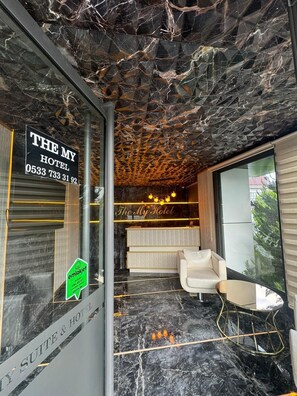 Un hall d’hôtel moderne avec un sol en marbre, un comptoir d’accueil et un espace salon.