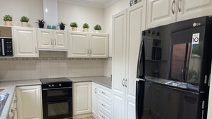 Une cuisine moderne avec des meubles blancs, un réfrigérateur noir et un four encastré.