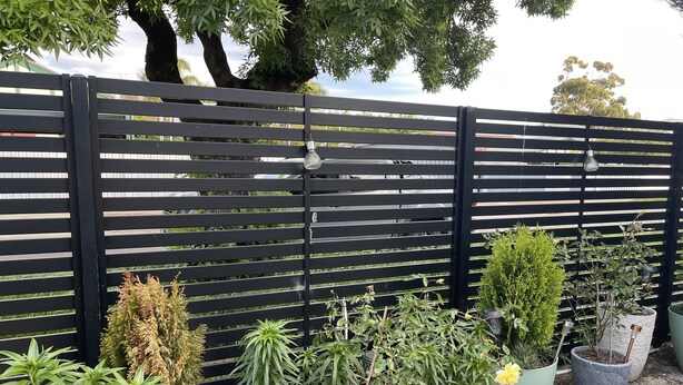 Une clôture noire avec des plantes en pot devant.