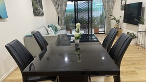 Un coin repas comprenant une table noire, six chaises, un canapé et un téléviseur.