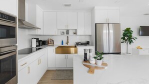 A modern kitchen with white cabinets, stainless steel appliances, and a marble countertop. - Modern Miami Home- 5 min from Coral Gables & Coconut Grove, 15 min from Brickell (Miami)