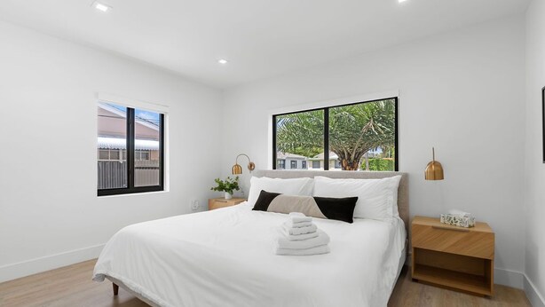 A bedroom with a large bed, a nightstand, a window, and a view of the outside. - Modern Miami Home- 5 min from Coral Gables & Coconut Grove, 15 min from Brickell (Miami)