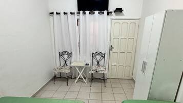 A small room with two beds, a TV, a table, two chairs, and a wardrobe.