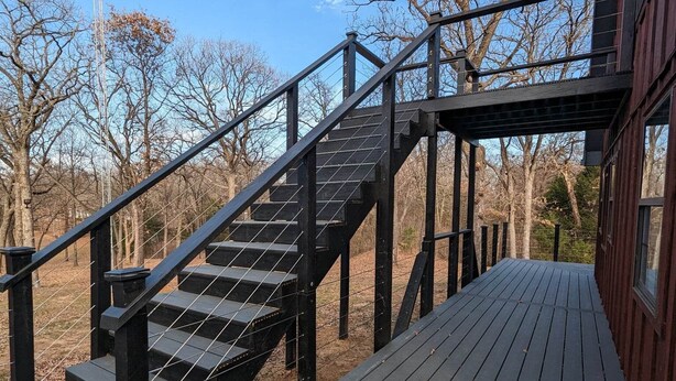 Eine Holzterrasse mit einer Metalltreppe zu einem Gebäude.