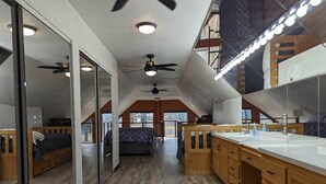 Ein modernes Schlafzimmer im Loft-Stil mit einem großen Bett, einem Schminktisch mit Spiegel und einem Deckenventilator.