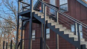 Ein rustikales Holzgebäude mit einer Metalltreppe, die zu einem Fenster im zweiten Stock führt.
