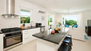 Een moderne keuken met een centraal eiland, een ingebouwde oven en een groot raam met uitzicht op groen.