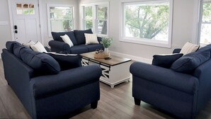 Un salon avec deux canapés bleu foncé, une table basse et un meuble blanc.