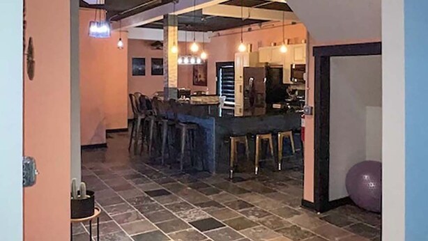 Une cuisine spacieuse avec un coin bar, un éclairage moderne et un plafond apparent laissant voir les conduits.