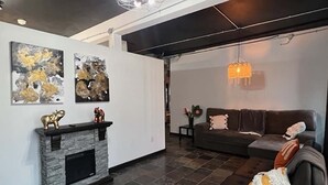Un salon moderne avec une cheminée, un canapé et des œuvres d’art accrochées aux murs.