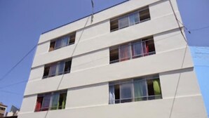 Un edificio de varios pisos con fachada plana y ventanas rectangulares.