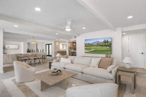 A spacious living room with a large sofa, a coffee table, and a dining area with wooden furniture. - Modern estate w/heated pool & outdoor kitchen (Paradise Valley)
