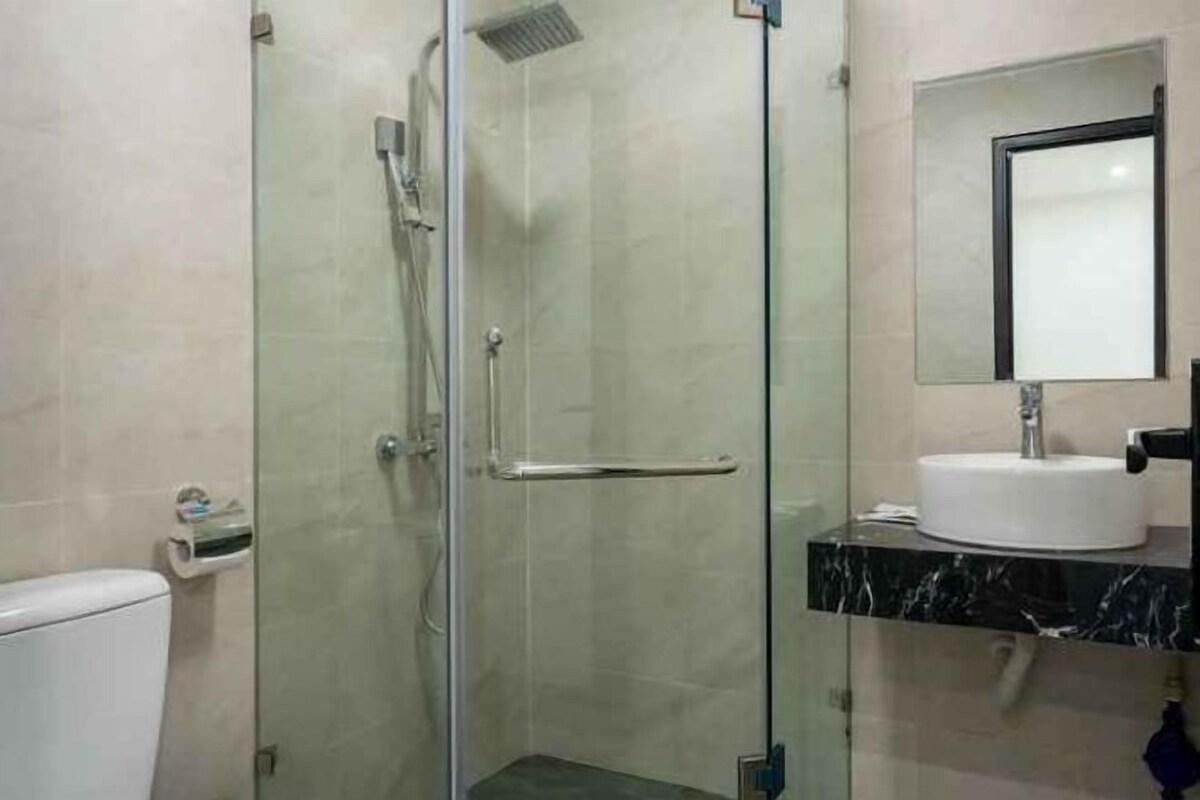 Un baño con cabina de ducha de vidrio, un lavabo blanco y un espejo encima.