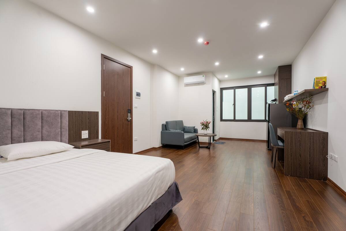 Une chambre d’hôtel moderne, dotée d’un grand lit, d’un canapé, d’un bureau et offrant une vue sur la ville.