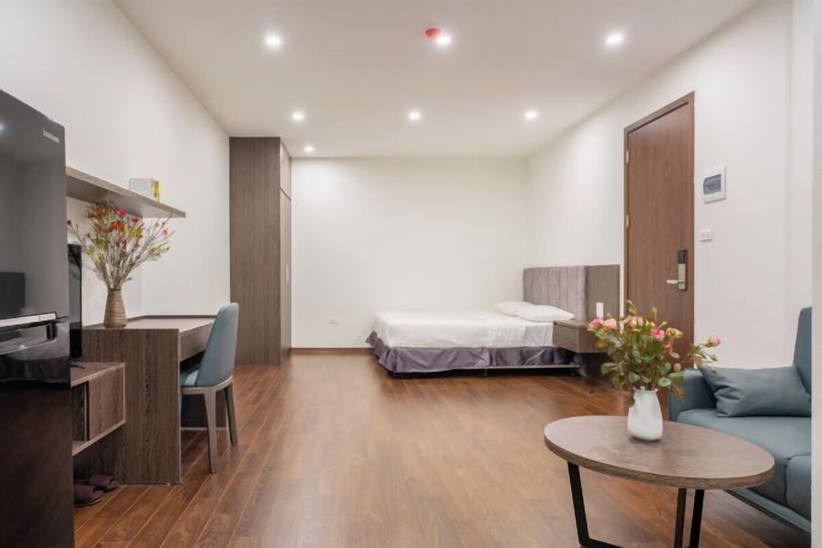 A compact room with a bed, a desk, a chair, a small table, and a sofa.