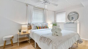 A bedroom with a bed, bedside table, lamp, and a ceiling fan.
