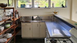 Cozinha com fogão a gás, pia e janela com vista para um jardim.