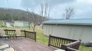 Une terrasse en bois avec des meubles d’extérieur et des poubelles.