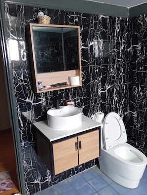A modern bathroom with a black and white marble backsplash, a wooden vanity with a sink, a mirror, and a toilet. - CloudView Snoopy Theme, Golden Hills Resort Genting, Genting Highlands (Genting Highlands)
