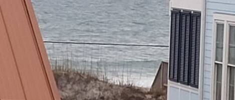 Une maison située sur la côte, dotée d’un toit en pente, d’un balcon et offrant une vue sur l’océan.