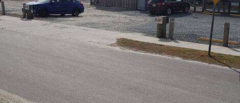 A parking area with a blue car and a trailer, a building with a ramp, and a 'NEW TRAFFIC PATTERN AHEAD' sign.