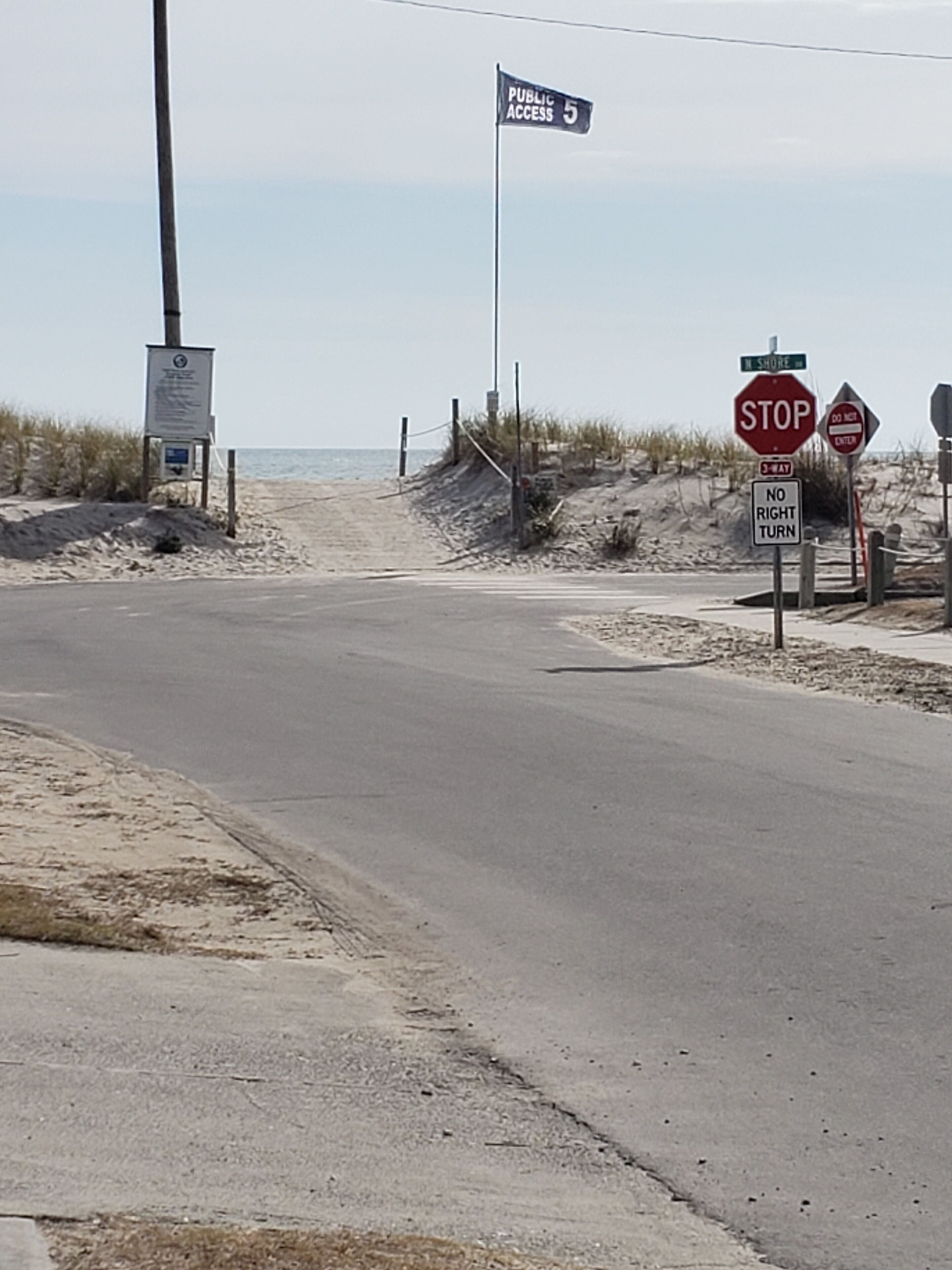 A beach road with a stop sign, a 'No Right Turn' sign, and a 'Do Not Enter' sign.