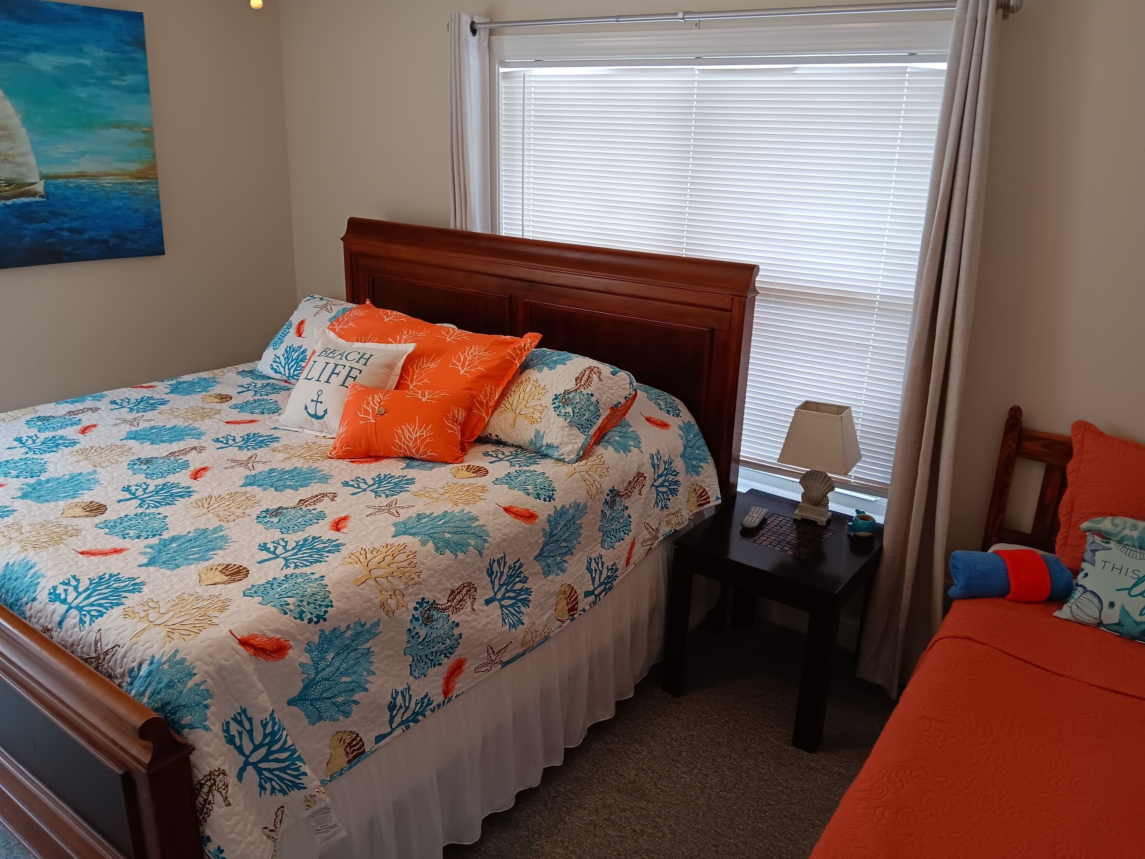 Un dormitorio con cama, mesita de noche, lámpara y ventana con persianas.