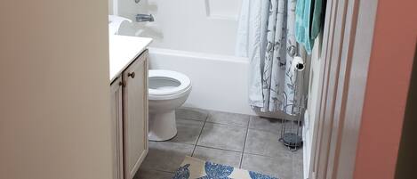 A bathroom with a toilet, bathtub, and shower curtain.