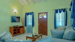 A living room with a sofa, a coffee table, a TV, and a wooden cabinet. - Modern two bedroom, 2 bathroom near Jolly beach for a peaceful stay. (St Mary's Parish)