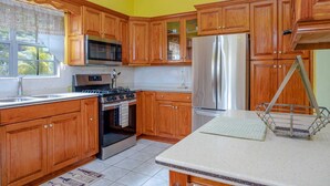 A kitchen with wooden cabinets, stainless steel appliances, and a window with a view. - Modern two bedroom, 2 bathroom near Jolly beach for a peaceful stay. (St Mary's Parish)