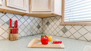 A kitchen counter with a cutting board, a knife, and a knife block. - Kindness - Wheelchair Accessible,BOK cent, Expo Sq (Tulsa)