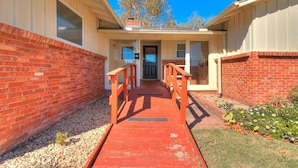 A building with a red brick exterior, a wooden walkway leading to a door, and a clear blue sky. - Kindness - Wheelchair Accessible,BOK cent, Expo Sq (Tulsa)