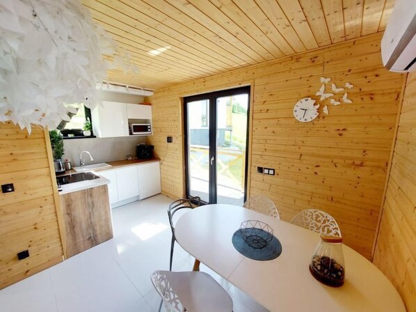 A modern kitchen with wooden walls, a white countertop, and a dining area with a white table and chairs.