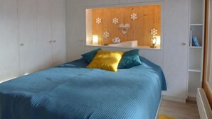 Un dormitorio con cama, mesita de noche y estante empotrado con objetos decorativos.