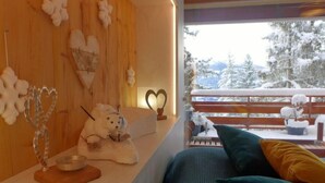 Una habitación acogedora con una pared de madera, una ventana con vistas nevadas, un sofá y elementos decorativos.