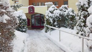 Un sendero cubierto de nieve que conduce a un edificio con un letrero rojo y varias ventanas.