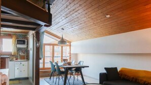 A modern living room with a sofa, coffee table, and dining area with chairs and a table. - Les Genets 163B by Interhome (Nendaz)