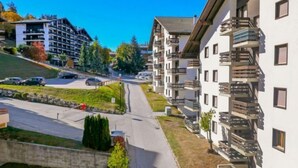 A residential area with modern apartment buildings, a road, and a parking lot. - Les Genets 163B by Interhome (Nendaz)
