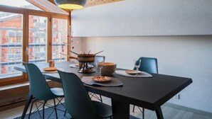 A modern dining area with a wooden ceiling, large windows, and a table set for four. - Les Genets 163B by Interhome (Nendaz)