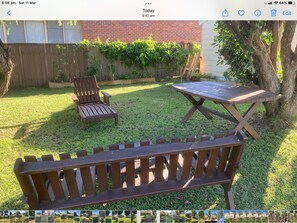 A backyard with a wooden bench, a wooden table, and a chair. - “Joy” cottage 10km from the Hunter Valley wineries, close to everything. (Cessnock)