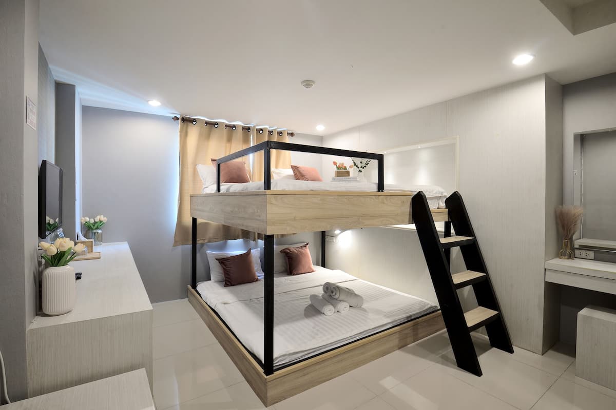 Un lit superposé avec une échelle, une table de chevet et un miroir.
