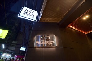 Das Außengelände des De Lux Bangkok Hotels mit einer auffälligen, beleuchteten Beschilderung.