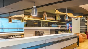 A modern kitchen with a white countertop, stainless steel appliances, and pendant lighting. - De Lux Bangkok Hotel (Bangkok)