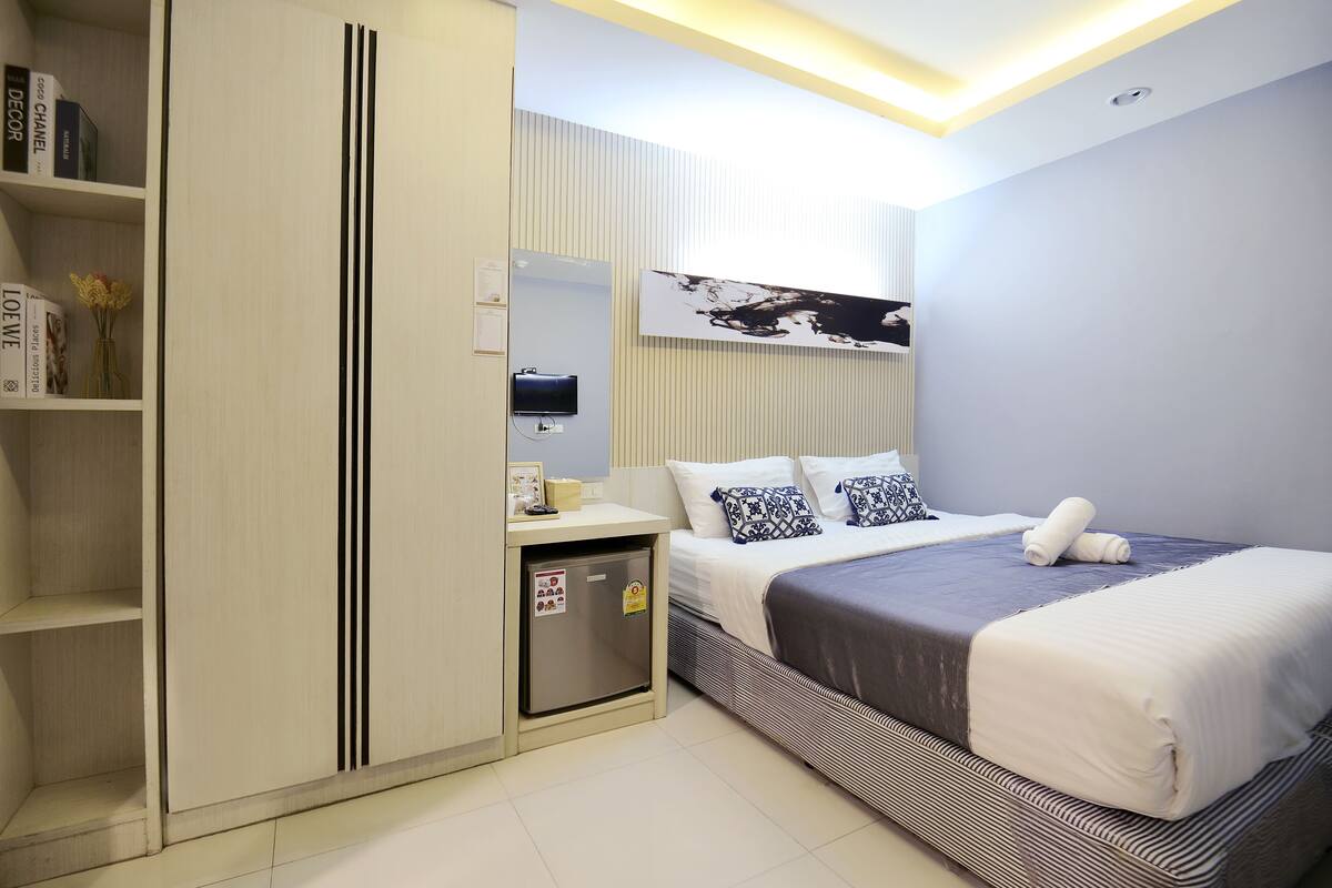 Une chambre d’hôtel comprenant un lit, un petit bureau, une armoire et un téléviseur fixé au mur.
